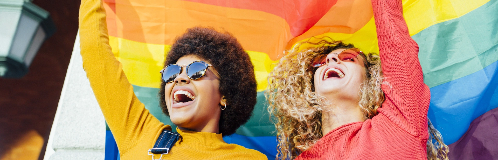 Dos mujeres ondean la bandera arcoíris