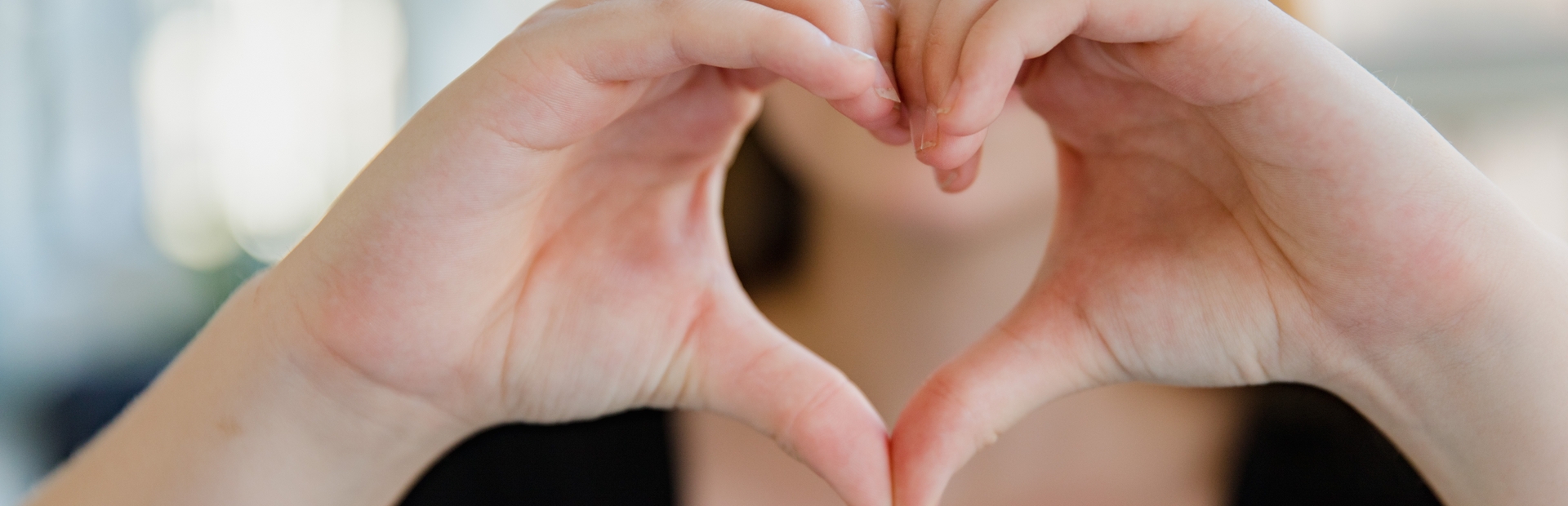 Mujer haciendo símbolo de corazón con sus manos