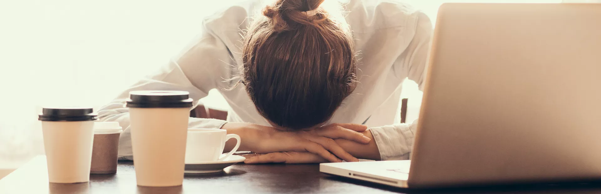 Mujer agobiada apoya su cabeza sobre sus manos frente al ordenador