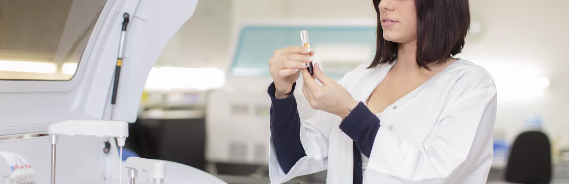 Mujer farmacéutica sujetando y observando una pipeta con un líquido dentro