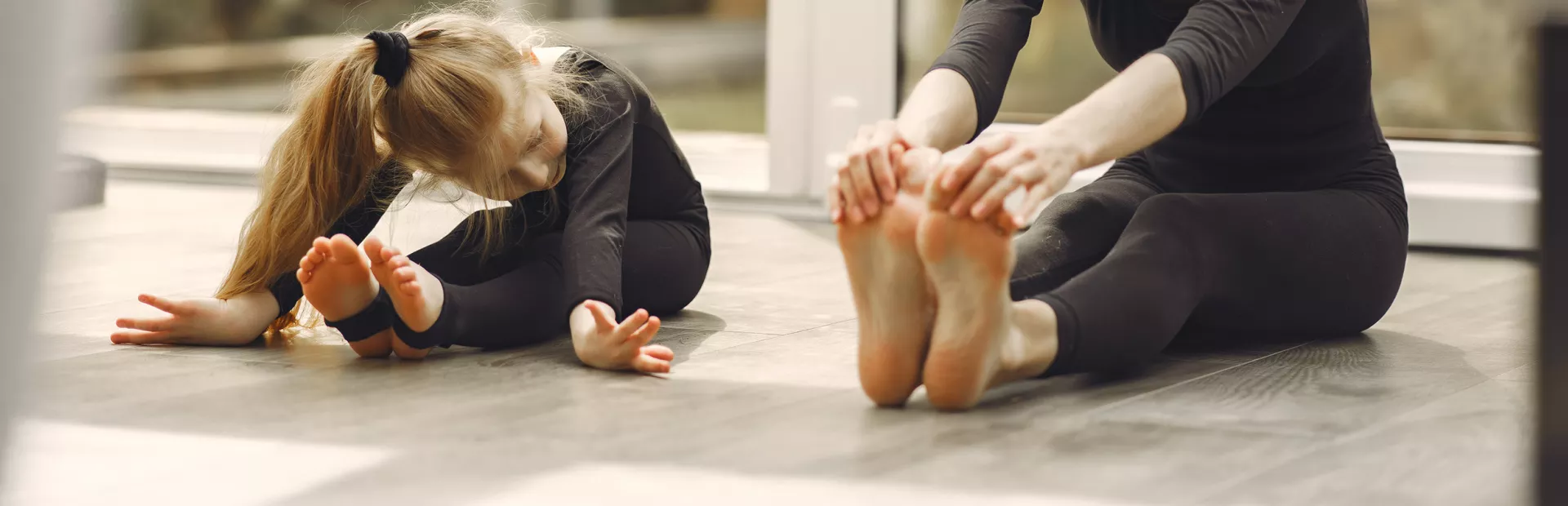 mujer y niña estirando los músculos de las piernas para bailar ballet