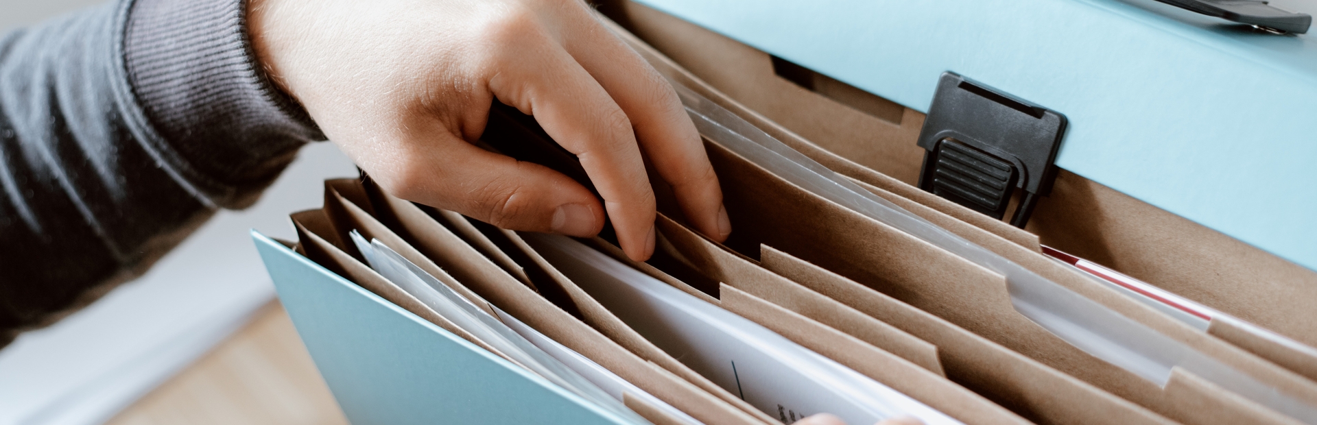 persona buscando entre las páginas de un archivador azul