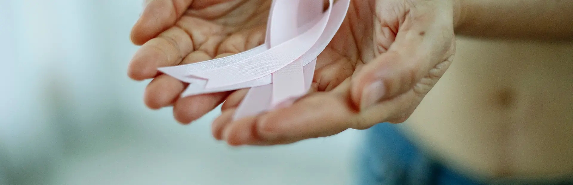 Manos sujetando un lazo rosa