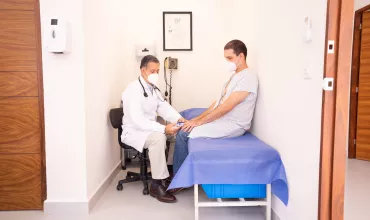 Doctor tomando la tensión a su paciente en una camilla