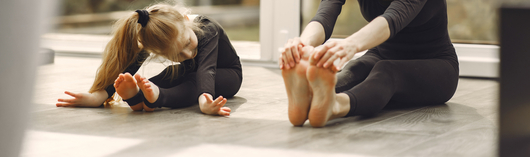 mujer y niña estirando los músculos de las piernas para bailar ballet
