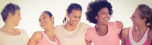 Cinco mujeres en fila abrazándose por los hombros y sonriendo 