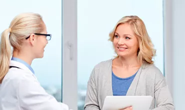Mujer paciente sonriendo a doctora que le está ofreciendo un diagnóstico