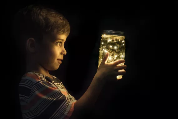 Niño observando luciérnagas en un frasco
