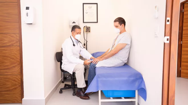 Doctor tomando la tensión a su paciente en una camilla