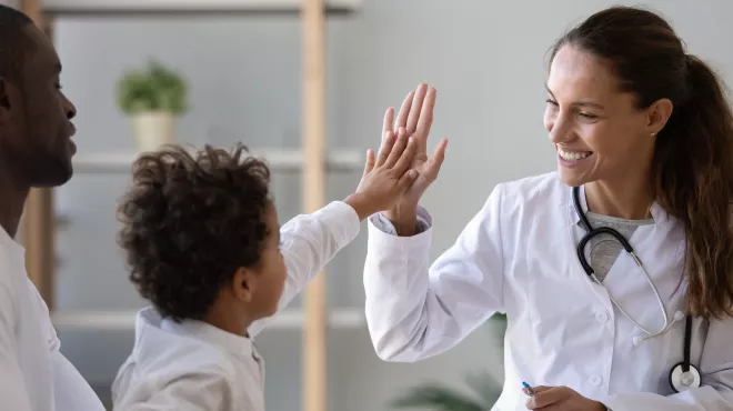 Un niño chocando la mano con su doctora