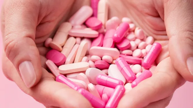 manos sujetando pastillas rosas