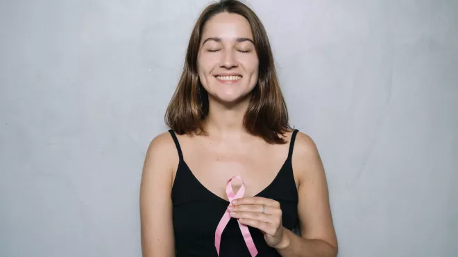 Mujer sonriendo con un lazo rosa