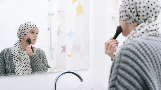 Paciente con cáncer arreglándose frente al espejo