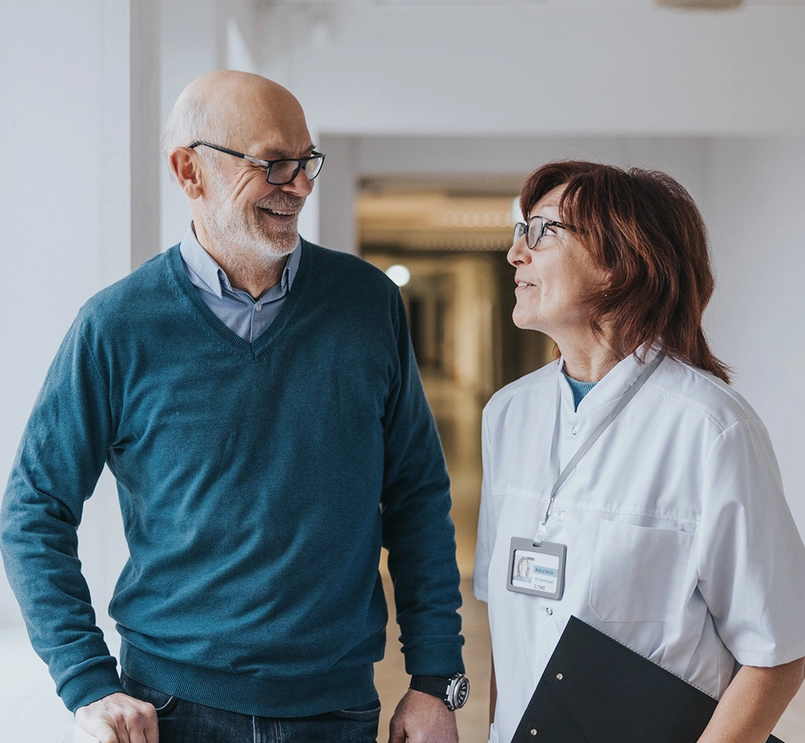 Naislääkäri ja miespotilas keskustelemassa käytävällä