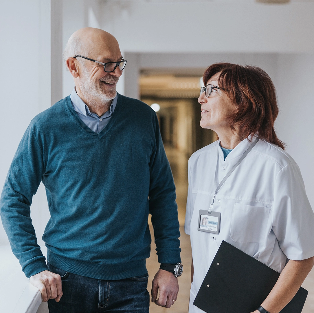 Naislääkäri ja miespotilas keskustelemassa käytävällä