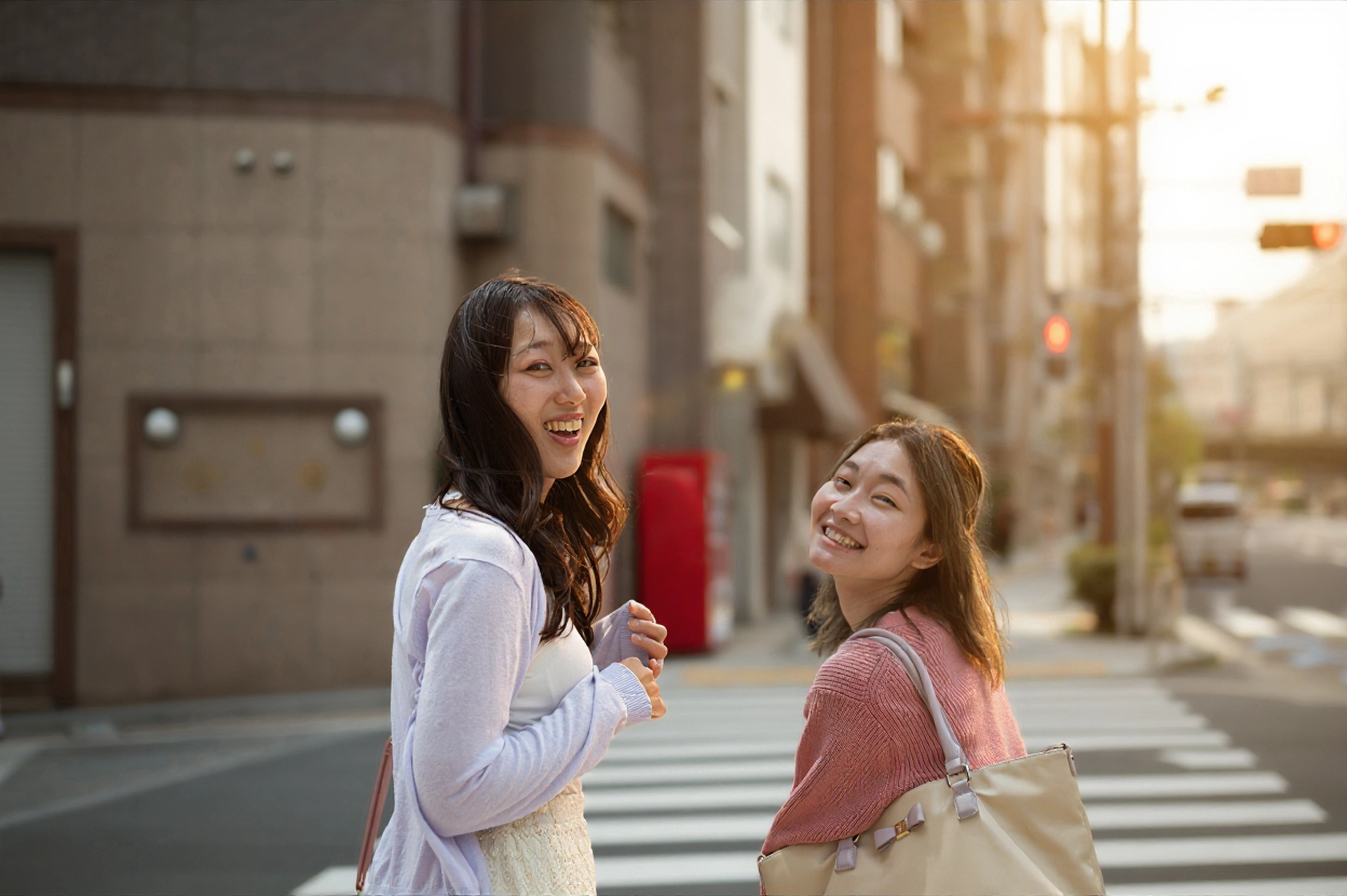 Two friends talking on a city crosswalk at sunset