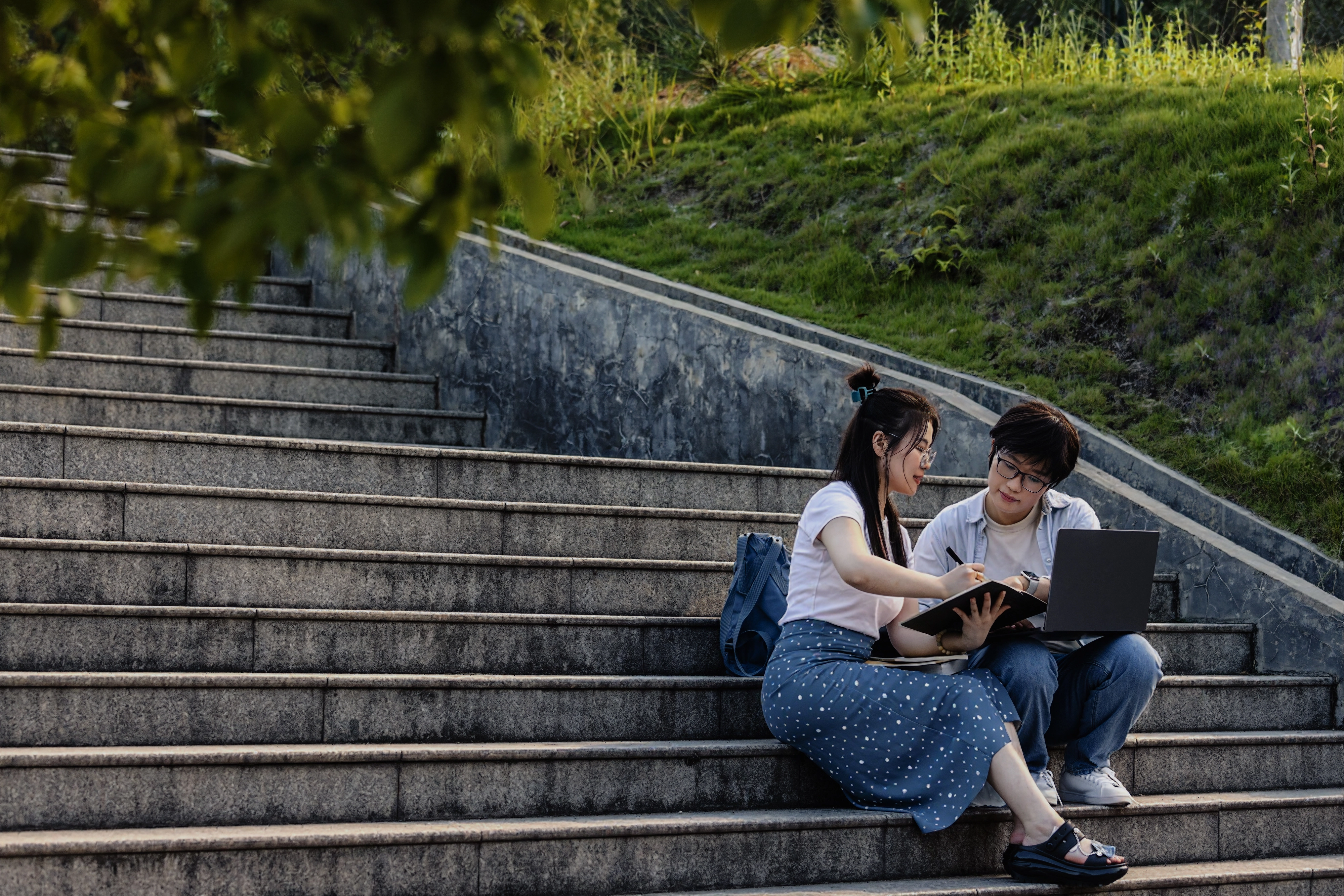 students-reading-on-outdoor-stairs-in-a-park