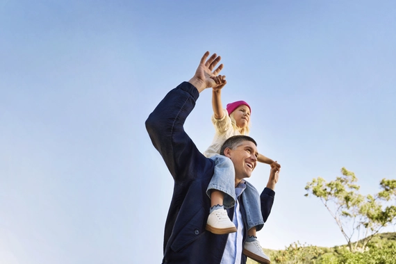 happy-parent-with-child-on-shoulders-under-clear-sky--1-