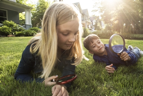 Bērni spēlējas ar palielināmo stiklu