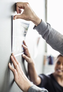  Cilvēki pielīmē pie sienas papīra lapu