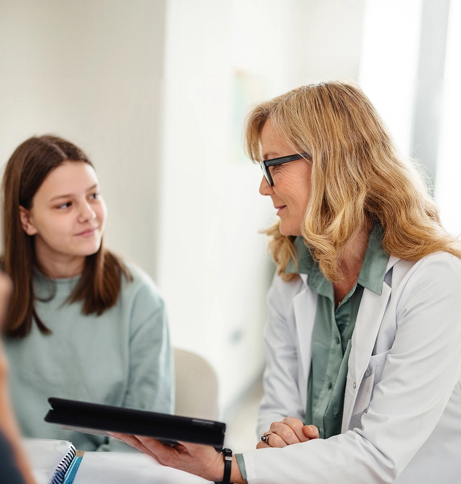 Pediatrician talking with a young teenager in the office