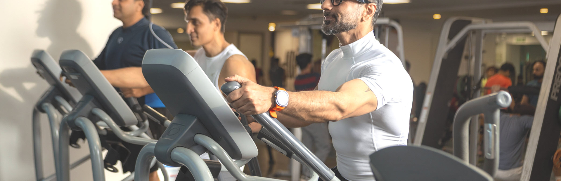3 mannen trainen in een sportschool op een cardio fitness apparaat