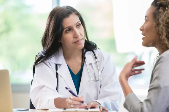 Vrouwelijke arts luistert naar vrouwelijke patient