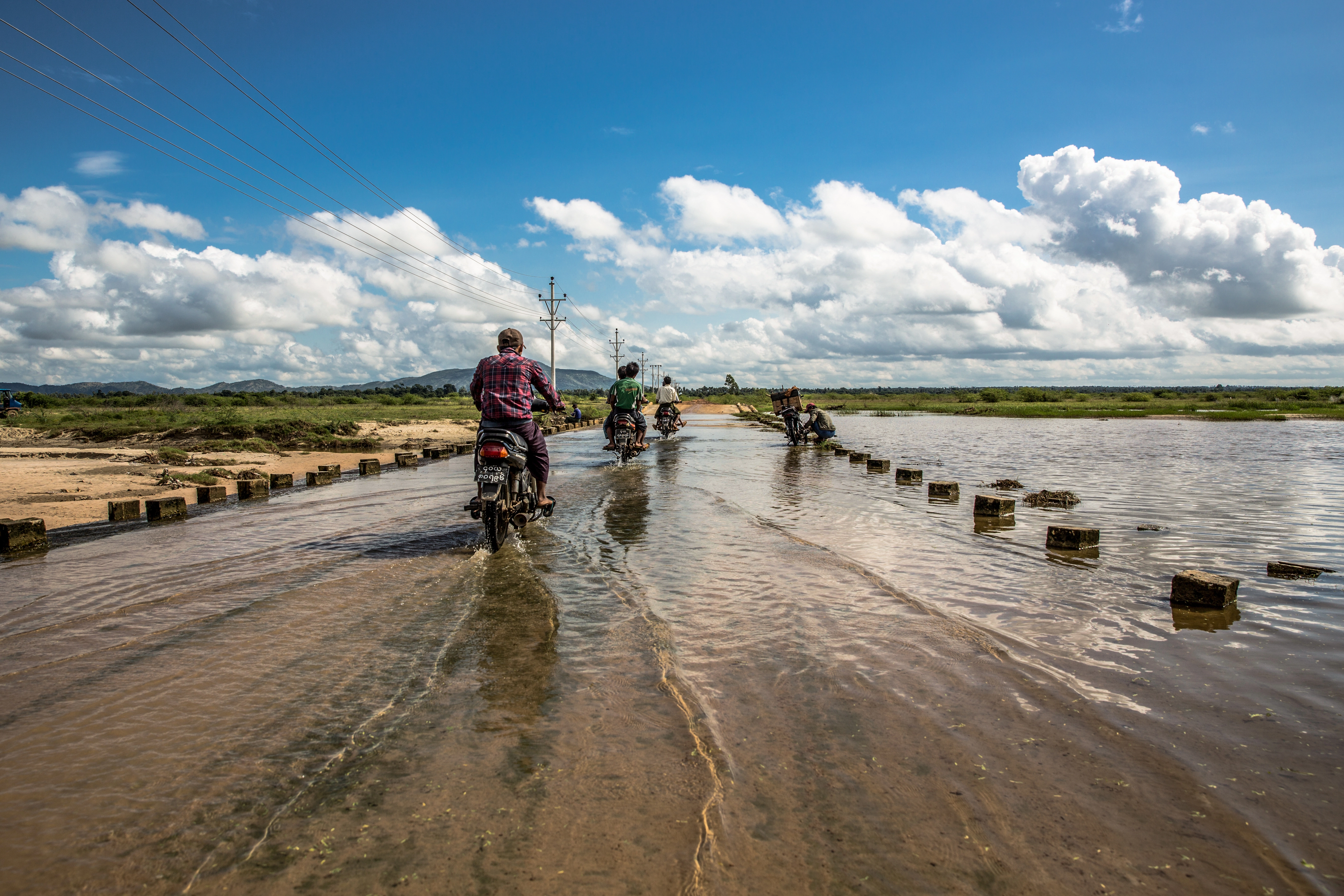Motorcycles driving on flooded street.