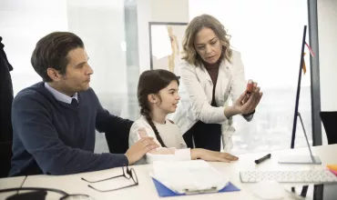 Compromisso da Novartis com os Doentes e Cuidadores - Médica a mostrar a um pai e uma filha como se usa um inalador