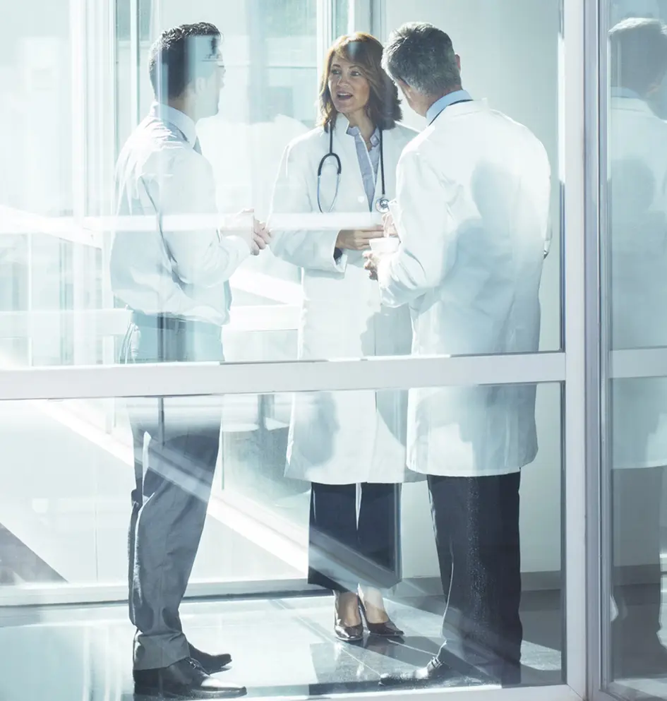 Doi medici și un om de afaceri discutând într-un spațiu luminos