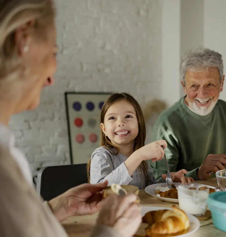 O familie zâmbitoare luând micul dejun împreună la masă