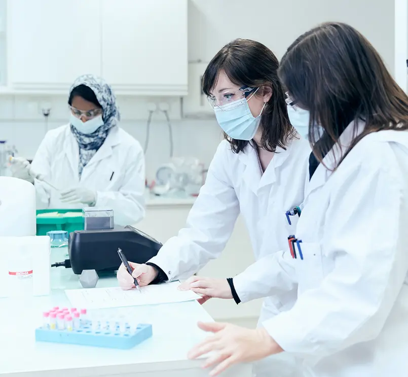 Cercetătoare care analizează date și eprubete în laborator