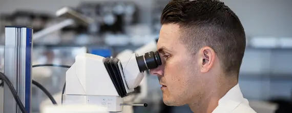 Cercetător utilizând un microscop de laborator