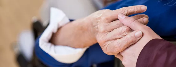 Pacijent i negovatelj drže ruke 