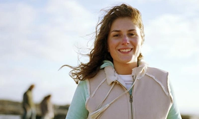 Kvinna går på promenad utomhus, det blåser. Foto.