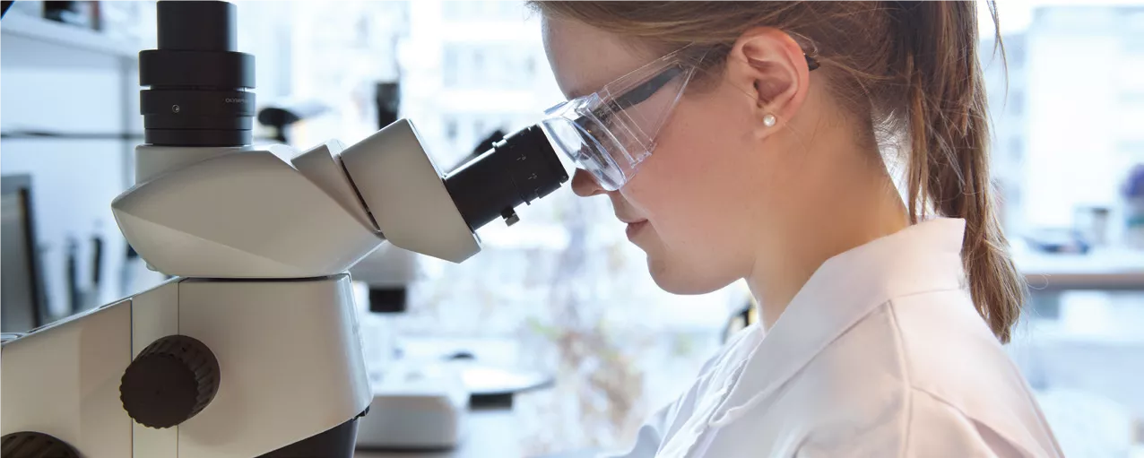En forskare tittar in i ett mikroskop i ett laboratorium. Foto.