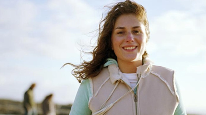 Kvinna går på promenad utomhus, det blåser. Foto.