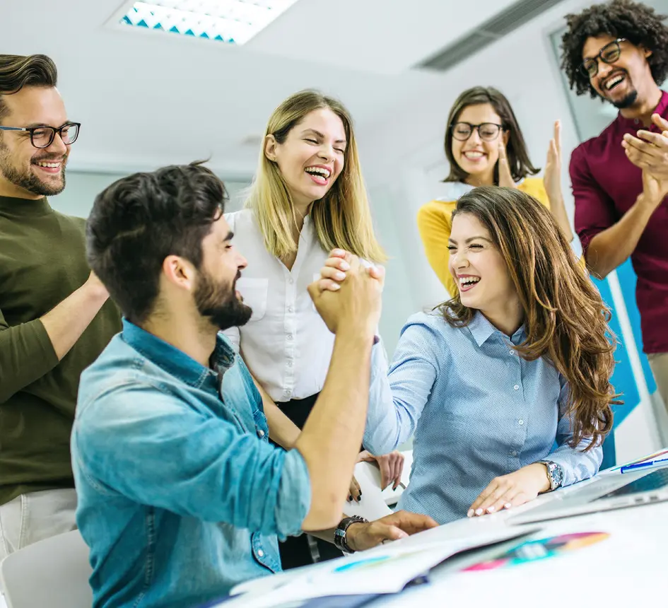 Group of coworkers celebrating success with a strong handshake in office