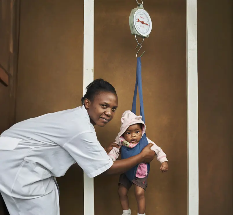 A health worker weighs a toddler