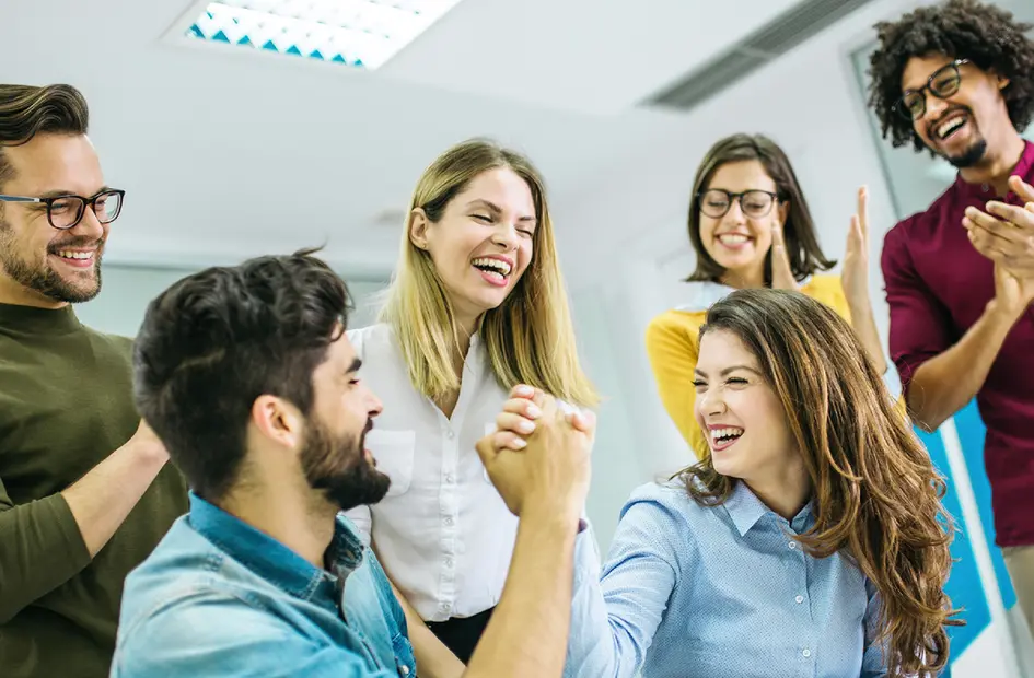 Group of coworkers celebrating success with a strong handshake in office