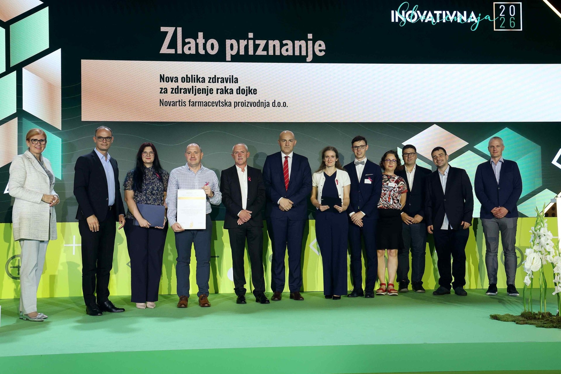 Novartis team standing on stage receiving the Gold Innovation Award in front of a presentation screen
