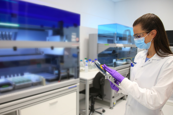 Scientist in mask and gloves using tablet in laboratory