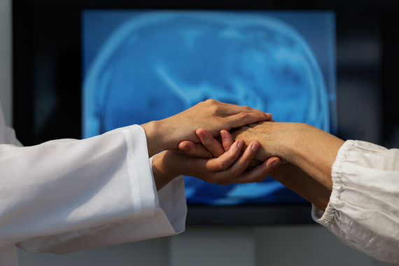 Doctors examining a patients hand with brain scan in background