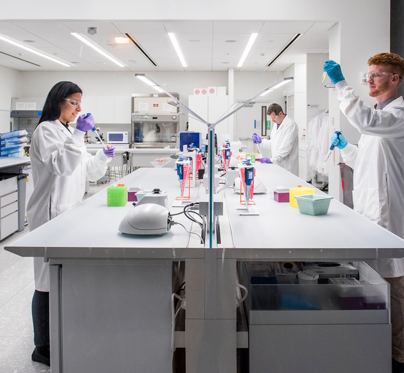 Znanstveniki v laboratorijskih haljah in rokavicah delajo v laboratoriju