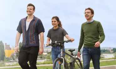 Mladi se sprehajajo po parku s kolesom