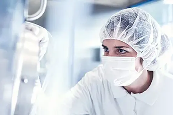 Znanstvenica v zaščitni opremi dela v sterilnem laboratoriju