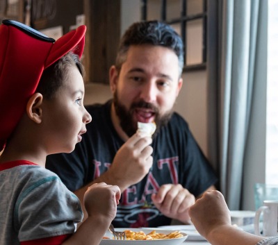 Young boy with father eating food at dinner table talking about peanut allergy treatment 