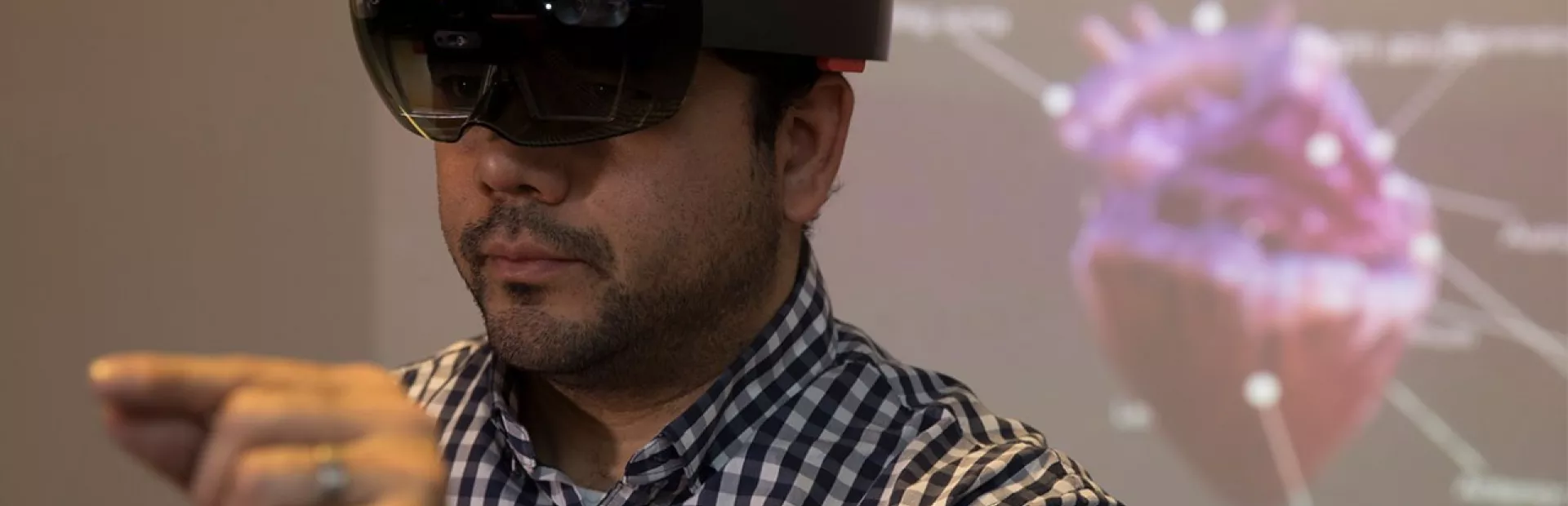 Man wearing AR glasses to manipulate a hologram of a heart