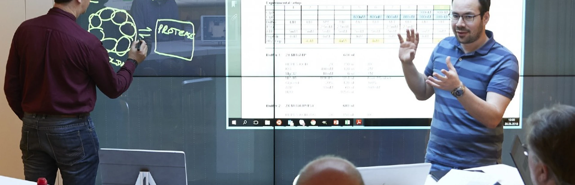 Novartis scientists Edward Oakeley (left) and Mevion Oertli use a plasma screen to present their findings to Novartis researchers.