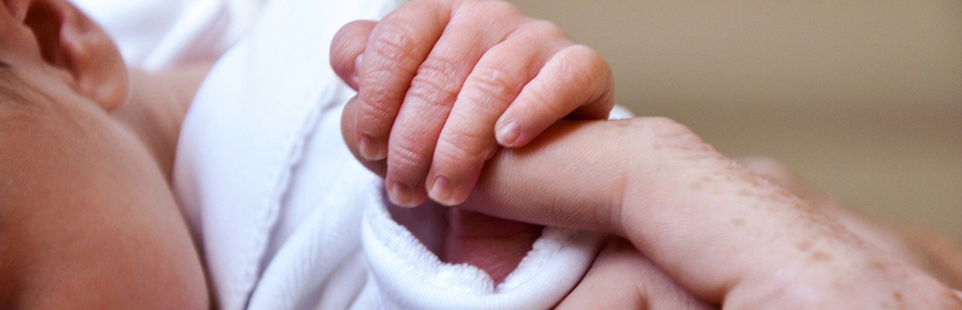 Baby's hand holding parent's finger